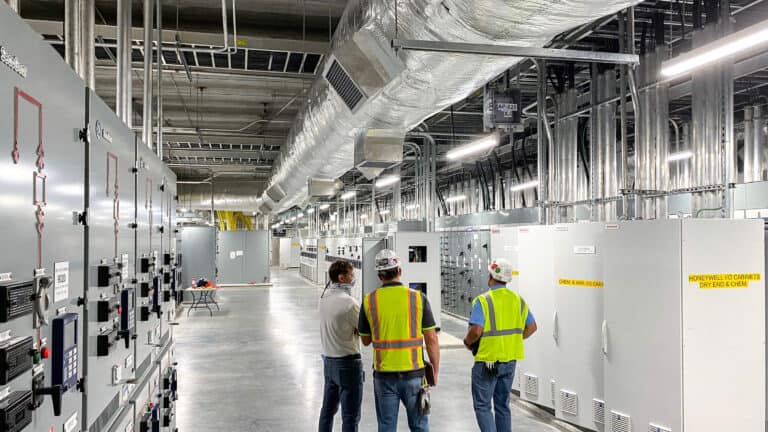 Two construction workers and employee discuss Paper Mill construction project