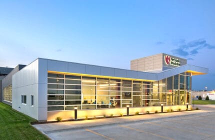 Nebraska Medicine clinic - exterior view of building with parking lot, building is lit at dusk