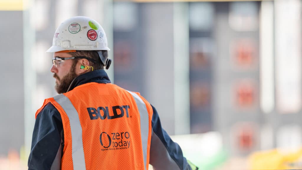 Construction worker on job site wearing safety vest and hard hat