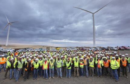 Portland General Electric Company - Tucannon River Wind Farm - Group of Employees Standing in Parking Lot Beneath Two Wind Turbines