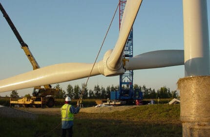 St. Olaf College - Wind Turbine Erection of Blades by Two Boldt Cranes. Boldt Employee in Foreground Guiding Lift